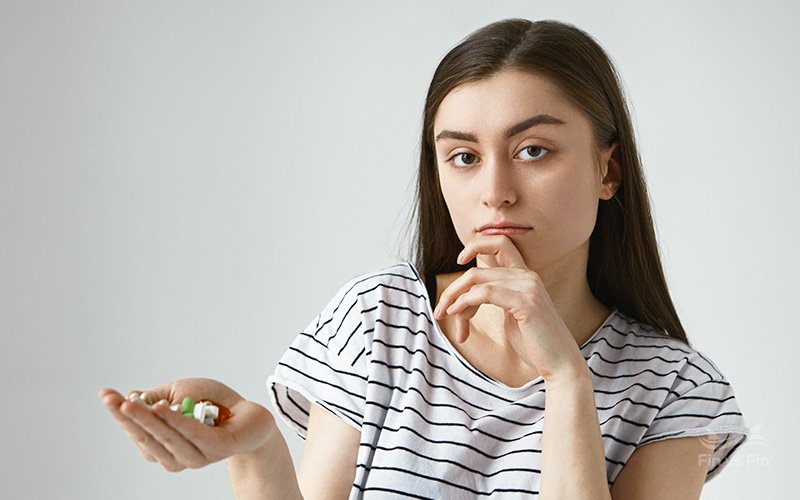 young brunette woman holding pills